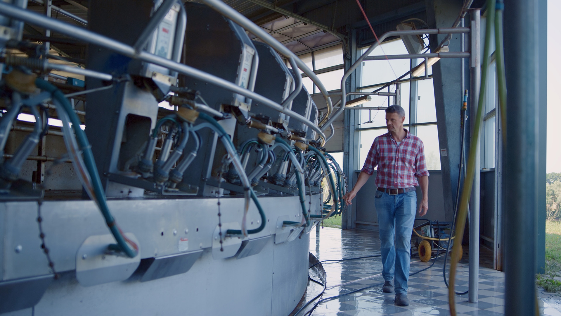 A man walking along the side of an agricultural machine, checking cable connections.
