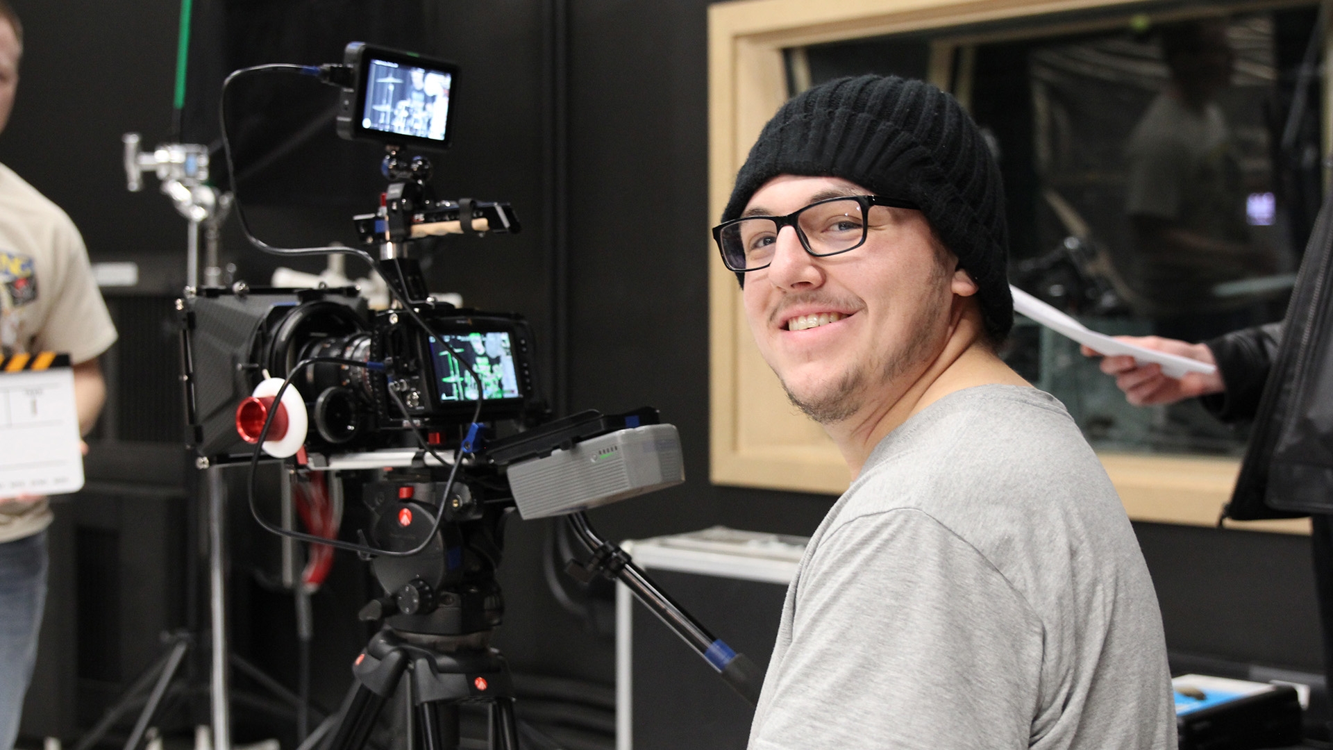 A media student sitting in front of a TV camera in a studio.