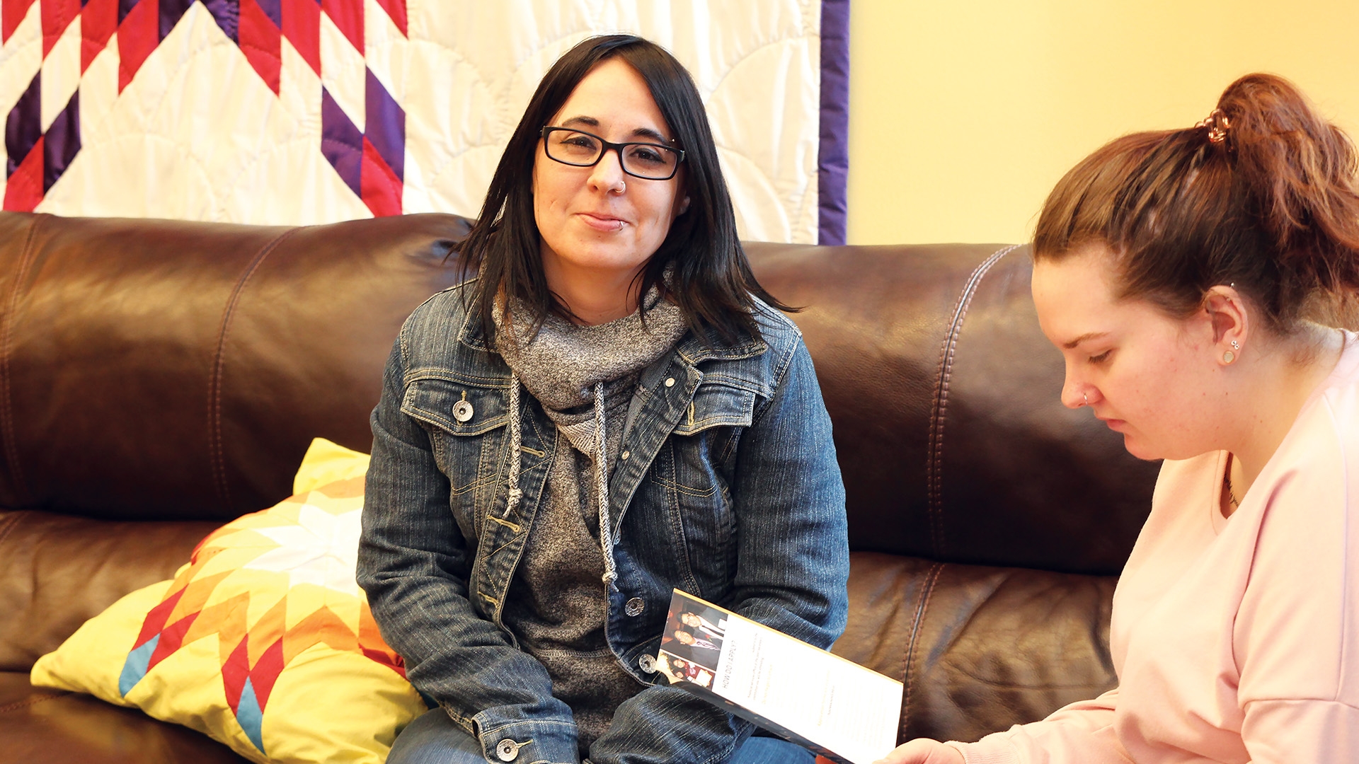 A social service worker student sitting on the couch inside the cultural centre.