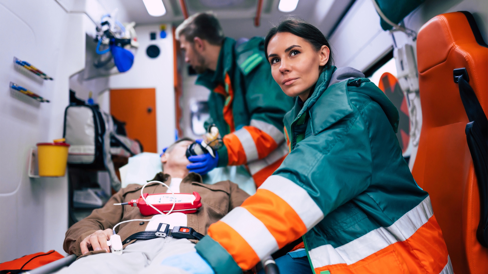 Doctors emergency or paramedics are working with a senior man patient while he lies on a stretcher in an ambulance.