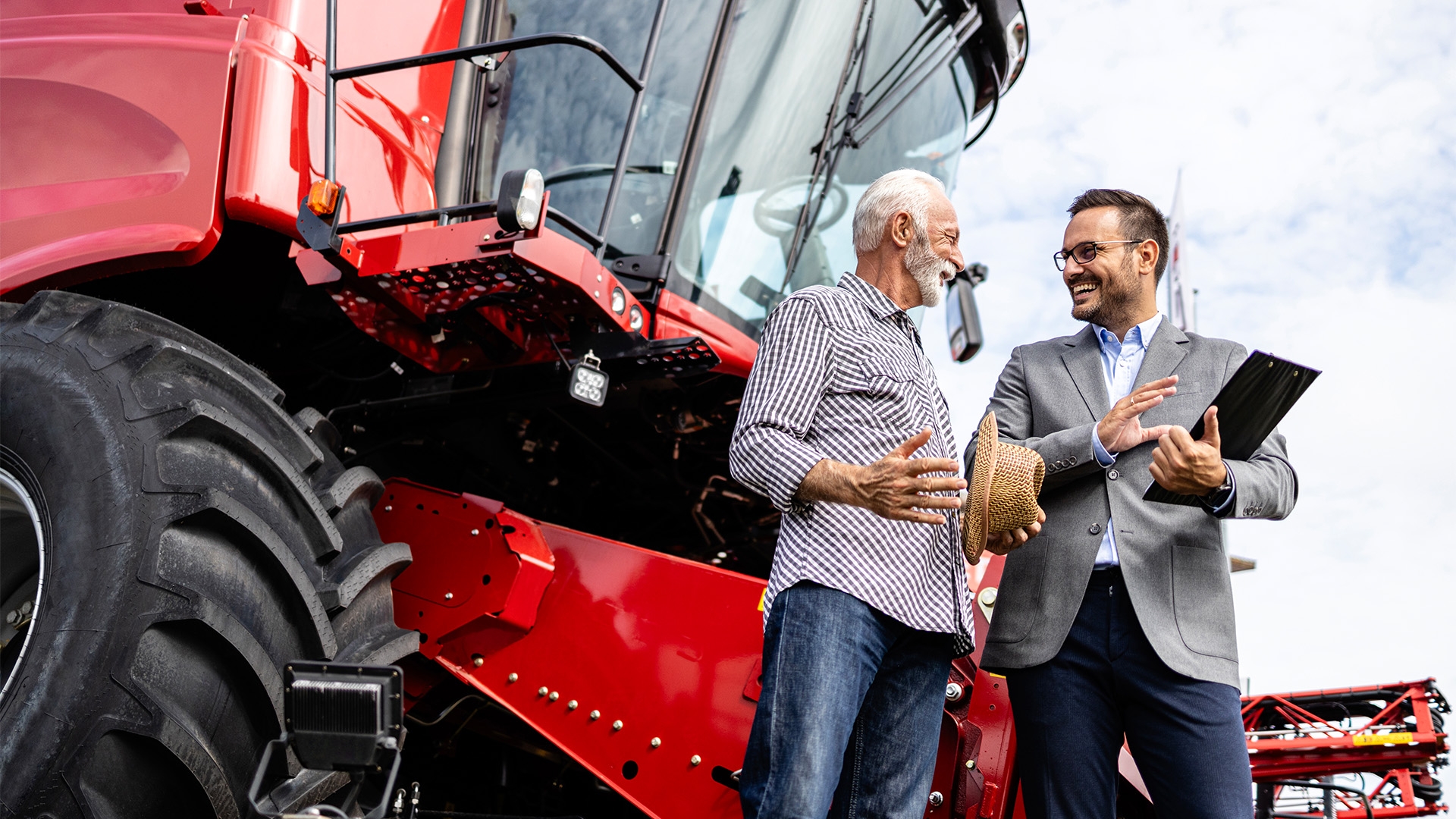 Two people standing in front of a red combine harvester.