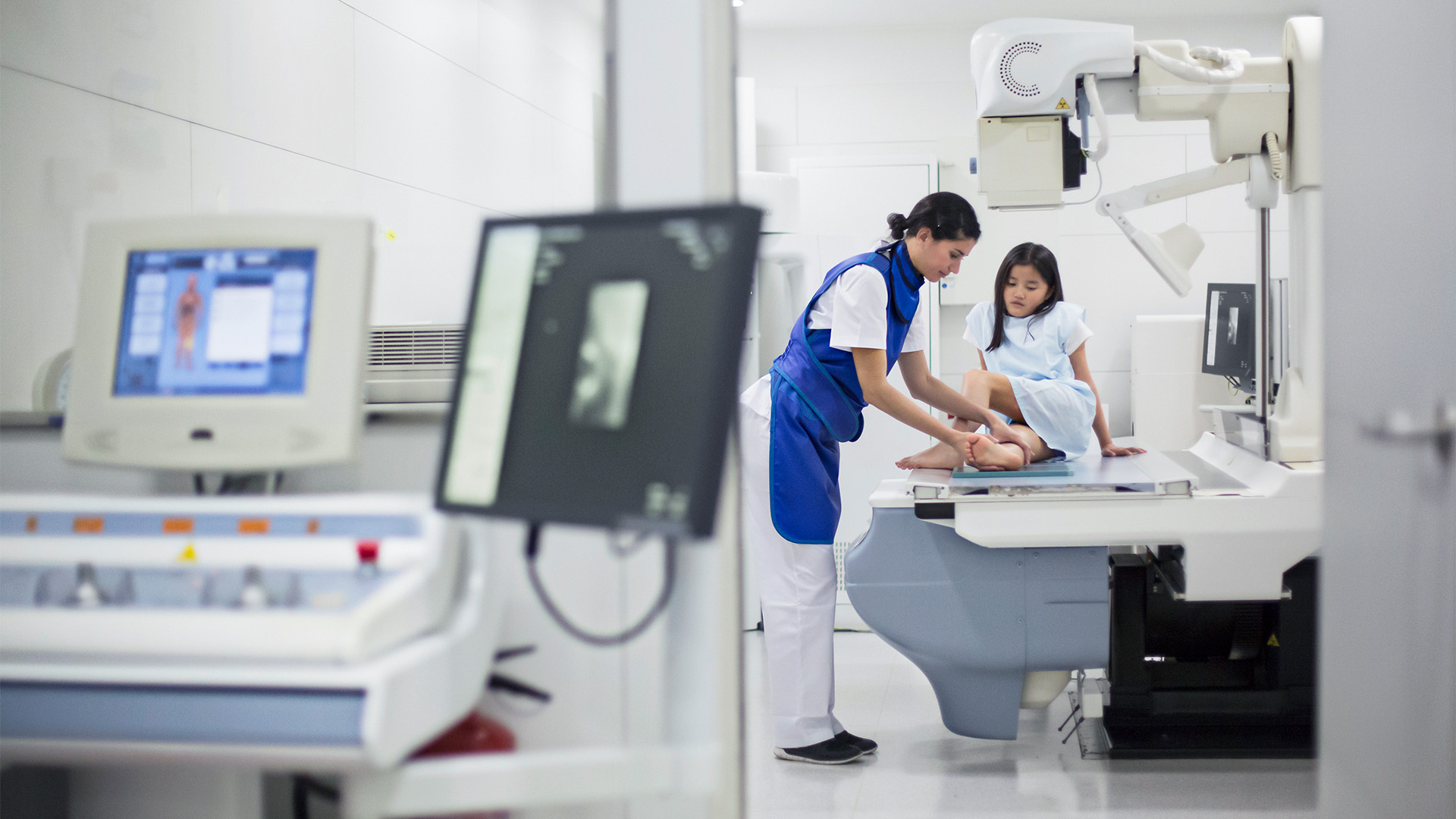 An x-ray technician positioning a child's ankle in an x-ray machine.