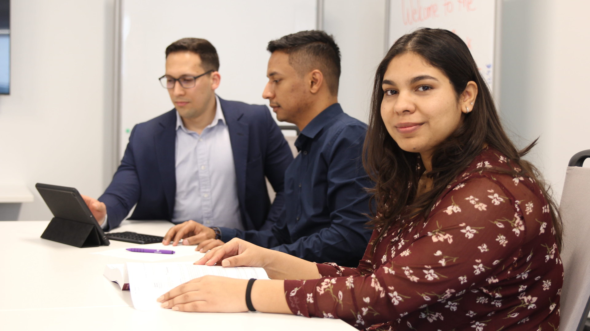 Three students sitting with one female looking at the camera