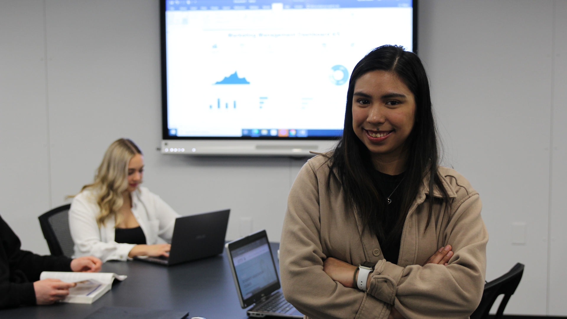Female student smiling at camera with her arms crossed
