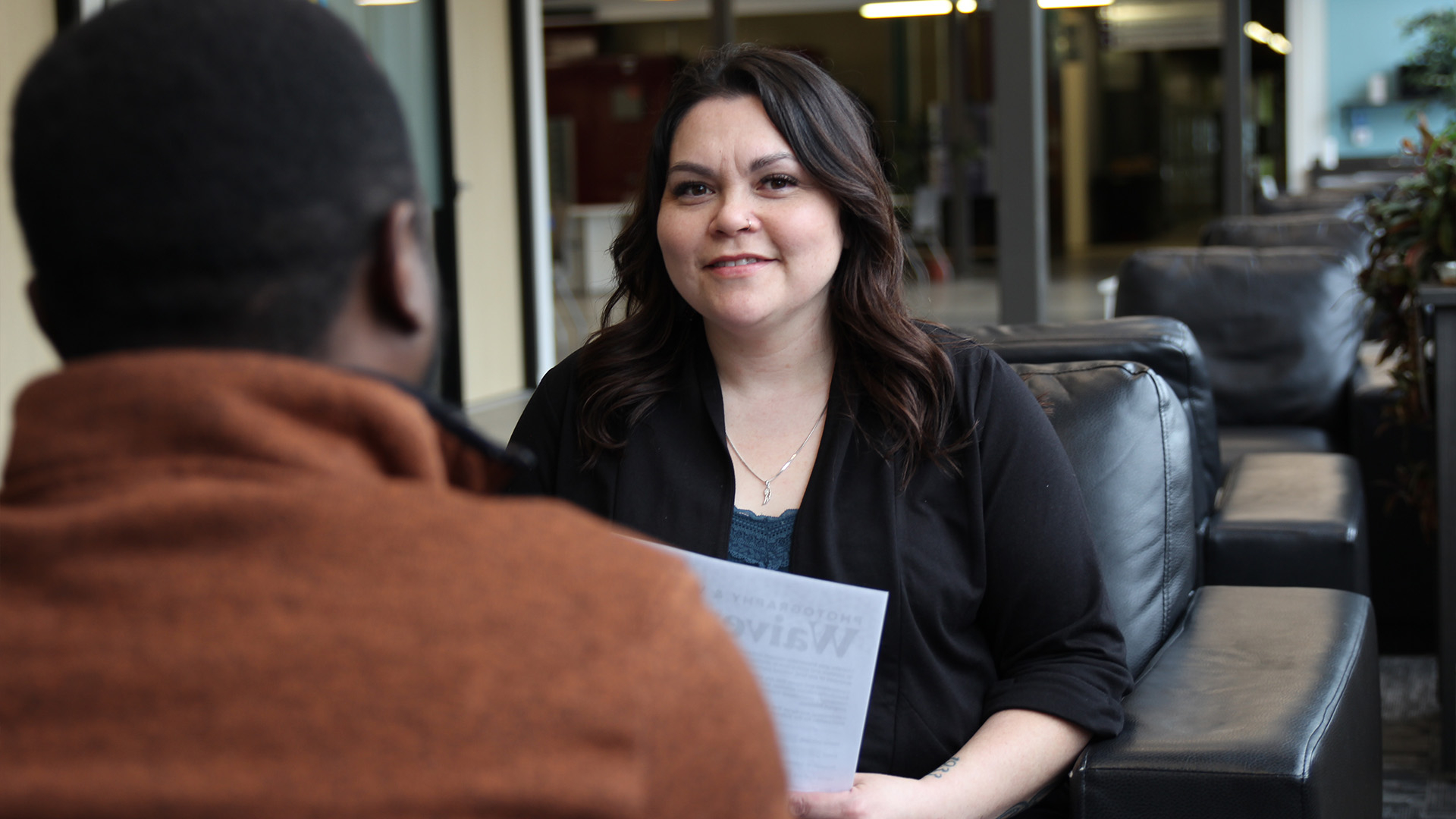 A social service worker sitting across from another person, reviewing documents together.