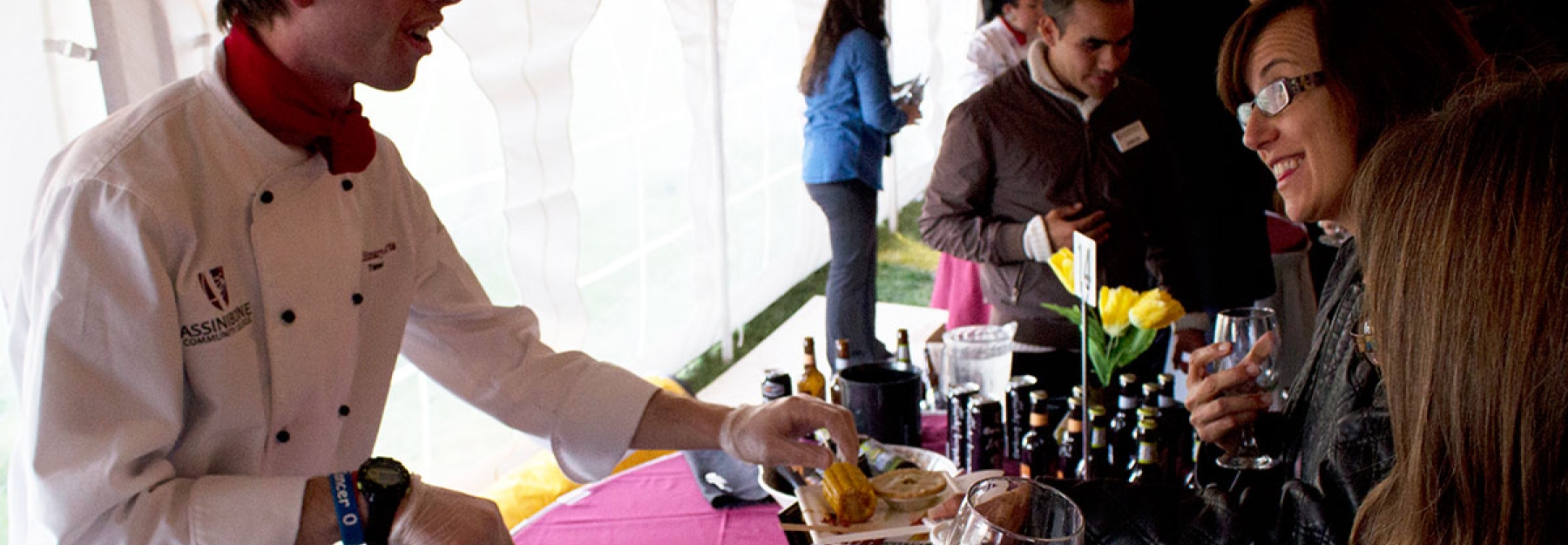 Student talks with guests while plating food.