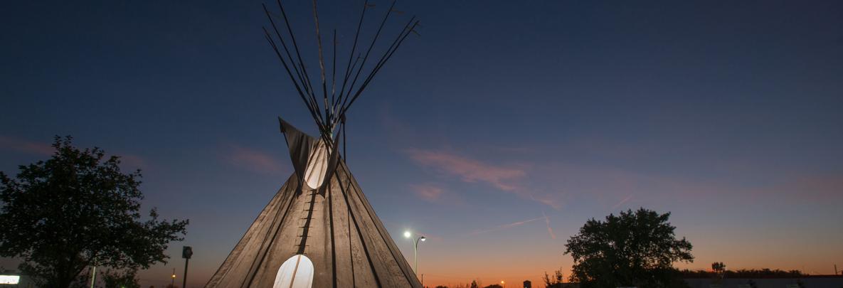 tipi at dusk outside of college's campus