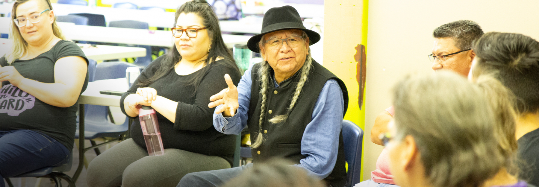An elder sits with a group of students.