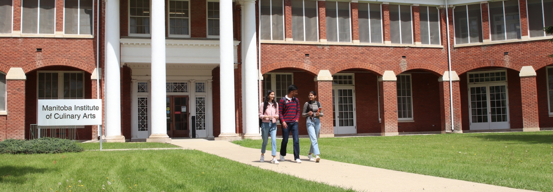Three students walk in front of the MICA building.