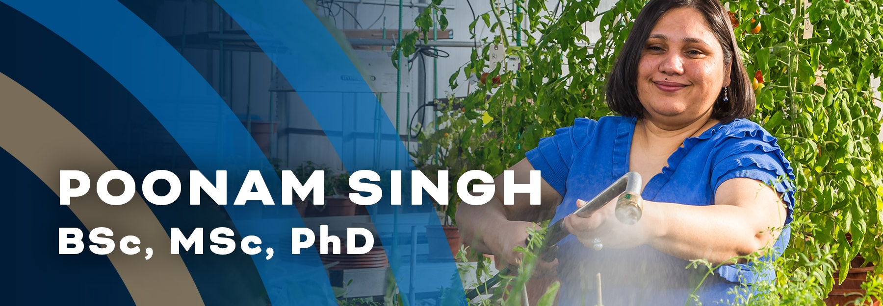 Dr. Poonam Singh stands just to the right of the centre of the photo with green plants in the background and foreground. She is wearing a blue t-shirt and holds a hose that is watering the plants in front of her.