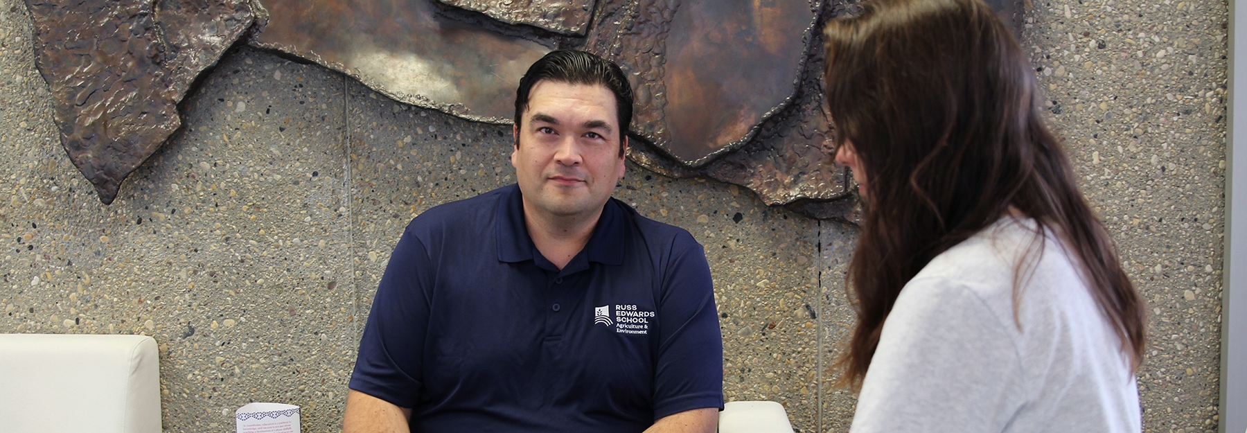 Trevor Dysart, an Assiniboine recruiter, sitting at a table with a prospective student, discussing program options.