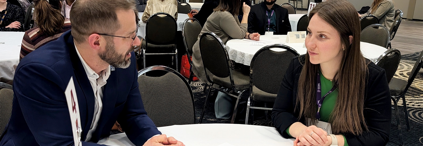 Two Assiniboine alumni sitting at a table during a networking event.