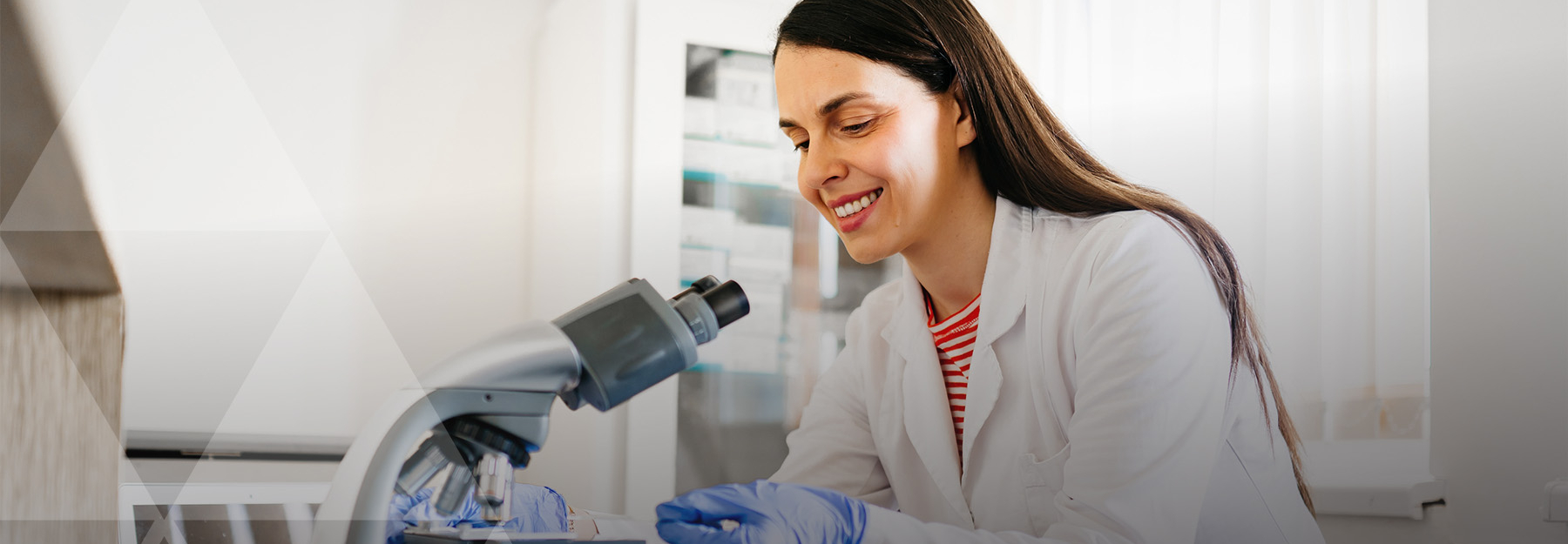 A woman in a lab coat putting a slide into a microscope.